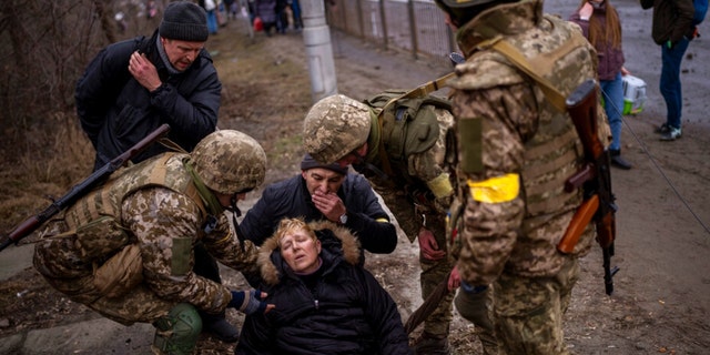 Ukrainian soldiers look after a semi-conscious woman after crossing the Irbin River while fleeing the city on the outskirts of Kyiv, Ukraine, Saturday, March 5, 2022. 