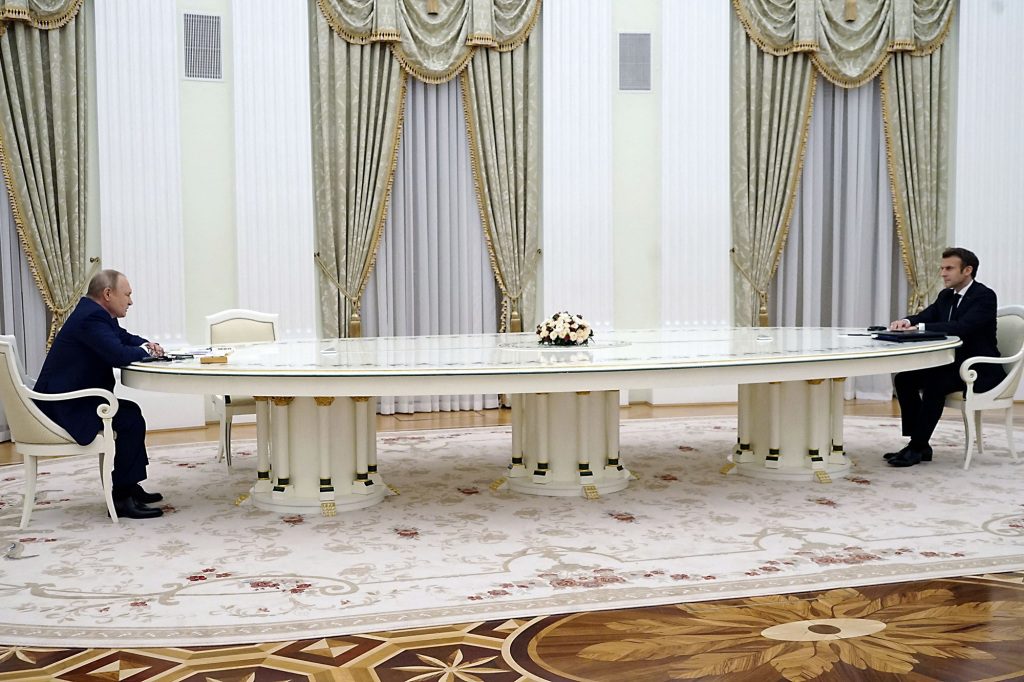 Putin and Marcon sitting across from each other at a table in Moscow