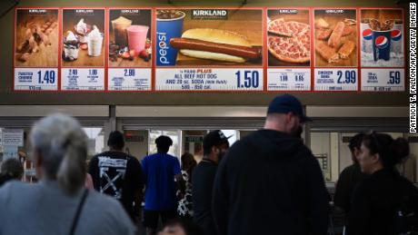 Customers wait in line to order the signs below for a $1.50 Hot Dog and Soda set from Costco Kirkland.
