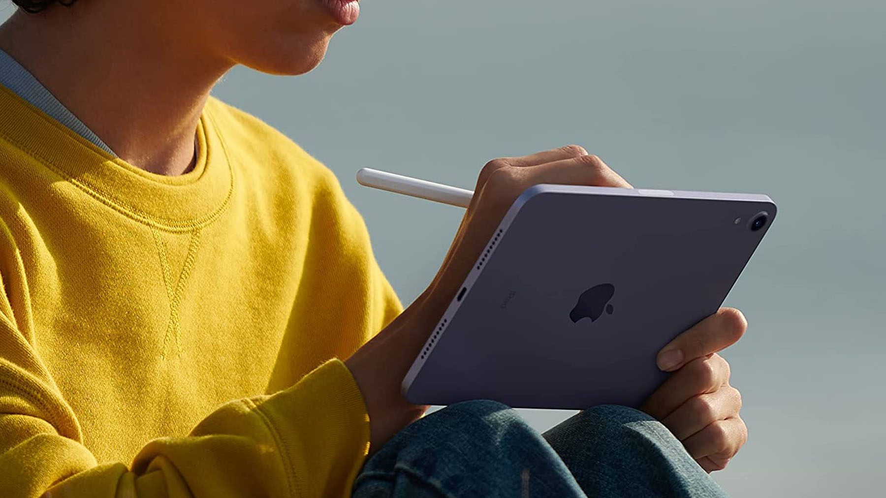 A shot of a person sitting on an iPad Mini while using an Apple Pencil