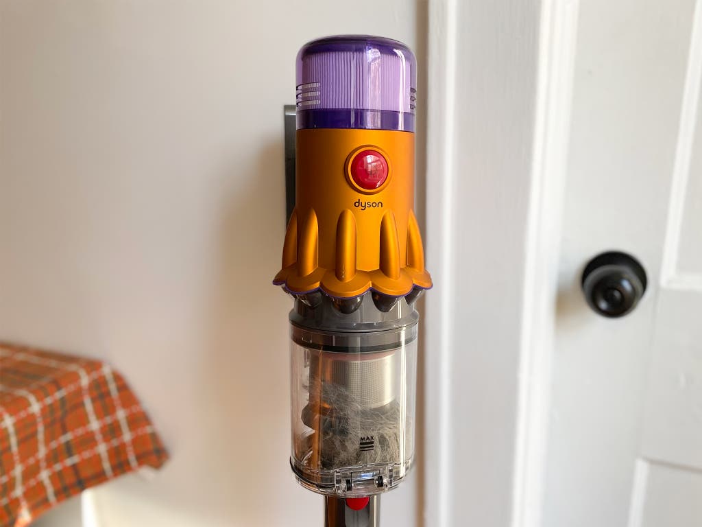 The top of the Dyson V12, displaying the purple top and yellow head with a bright circular red button.